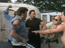 a group of men are standing in front of a trailer and one of them has a bandage on his arm