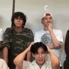 a group of young men are standing in a room and one of them is wearing a hat that says supreme