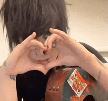 a person making a heart shape with their hands and a playing card on their back