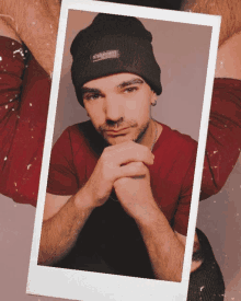 a man wearing a red shirt and a black beanie with the word street on it