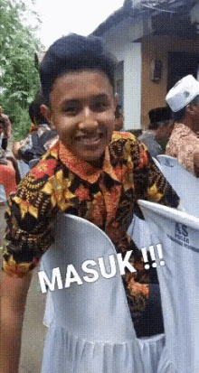 a young man in a colorful shirt is smiling while standing next to a white chair with the word masuk written on it