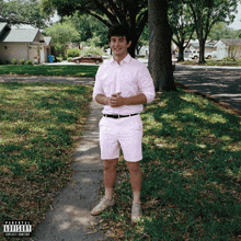 a man in a pink shirt and shorts is standing on a sidewalk with a parental advisory label