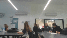 a group of people sitting at tables in a classroom with a sign on the wall that says ' a '