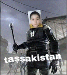 a man in a military uniform is holding a stick with the word tassaksistan written on the bottom