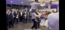 a man in a cowboy hat is carrying a woman on his shoulders at a wedding reception