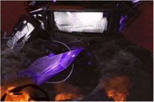 a purple object is surrounded by fire and smoke in a dark room