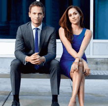 a man in a suit sits next to a woman in a blue dress