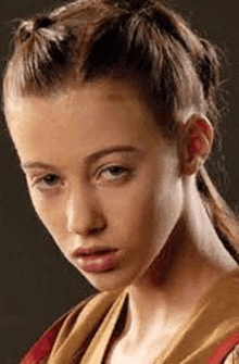 a close up of a woman 's face with a ponytail and a serious look on her face .