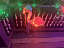 a pink flamingo with a blue hat and scarf is lit up on a porch