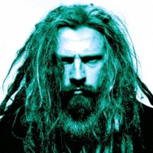 a man with dreadlocks and a beard is looking at the camera in a blue light .