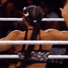 a woman in a braided ponytail is standing in a boxing ring with her arms outstretched .