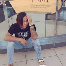 a woman wearing a metallica shirt sits on a tiled floor .