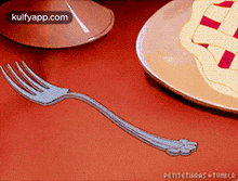 a fork is sitting on a table next to a plate of pie .