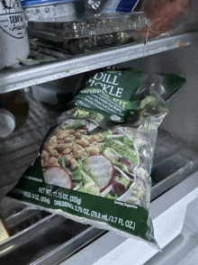 a bag of dill pickle product sits in a fridge