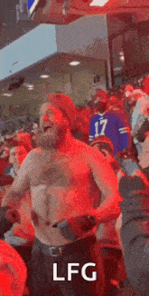 a shirtless man with a beard is dancing in a crowd at a sports game .