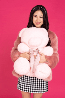 a woman in a pink fur coat holds a teddy bear