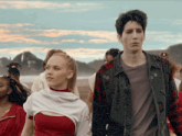 a man and a woman standing next to each other with the man wearing a plaid jacket with the letter o on the sleeve
