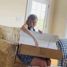 a woman sitting on a couch holding a cardboard box that says special delivery