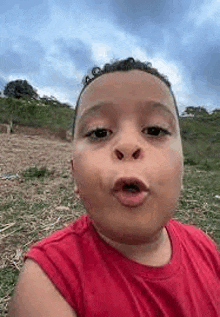 a young boy in a red tank top is making a funny face .