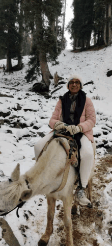 a woman is riding on the back of a white horse in the snow