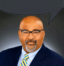 a man wearing glasses and a blue suit with a yellow and blue tie