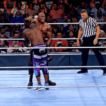 a referee stands in a wrestling ring with a man wearing a shirt that says " head table " on it