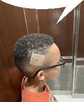 a young boy with glasses has a sticker on his head that says ' aa ' on it