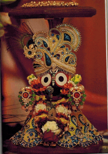 a close up of a statue of a deity with a peacock feather on his head