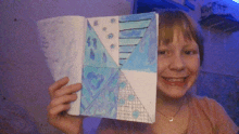 a girl is holding up a drawing of a snowflake