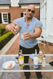 a man is pouring a drink from a shaker into a glass with a bottle of whiskey in the background