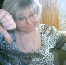 a woman wearing glasses and a leopard print shirt is giving a thumbs down