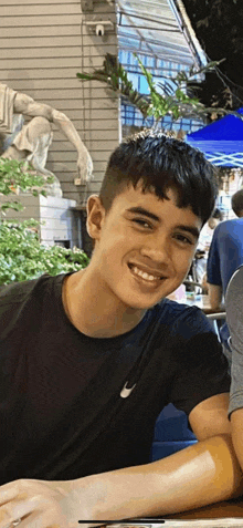 a young man in a black nike shirt smiles for the camera