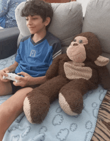 a boy playing a video game next to a stuffed animal