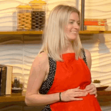 a woman wearing a red apron is smiling in front of a stack of books including one called eat like a man