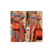 a woman is wearing an orange and blue dress with a high slit and a red purse .