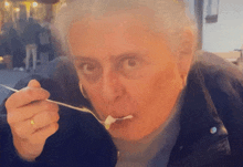 a woman is eating something with a spoon and a ring on her finger