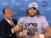 a man in a purple shirt that says macho man is being interviewed