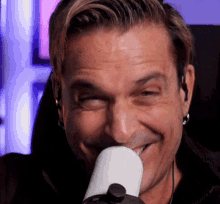 a man with a microphone in his mouth is smiling and making a funny face .