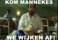 a man with a beard is sitting in a hospital bed with the words kom mannekes we wijken af