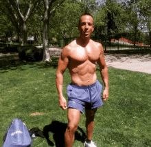 a shirtless man stands in a park next to a blue bag that says ' springs ' on it