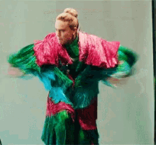 a woman wearing a pink and green dress is dancing