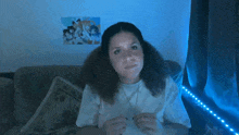 a woman is sitting on a couch in front of a blue light