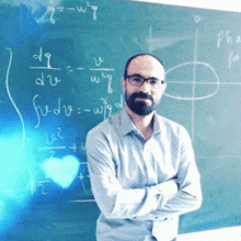 a man stands in front of a blackboard with equations written on it including g = w = q