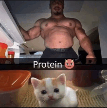 a muscular man is standing next to a kitten in front of a refrigerator door .