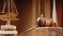 a wooden judge 's gavel sits on a wooden block in front of a scale of justice