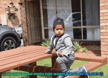 a little boy in a suit sits on a wooden picnic table with the words thank you so much for warm birthday wishes