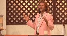a man in a pink suit stands in front of a fence