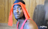 a man wearing an orange headband and a red tank top with imgplay written on the bottom right
