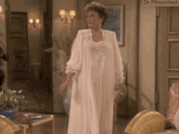 a woman in a white robe is standing in a living room with a sign that says dr pflaumisan