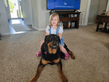 a little girl sits on the back of a dog in front of a tv that says life